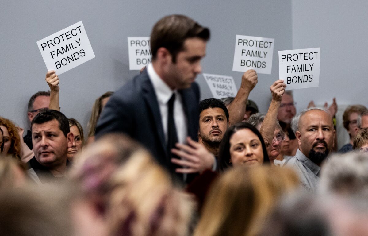 Attendees in support of the parental notification policy hold up signs during a Murrieta School Board meeting