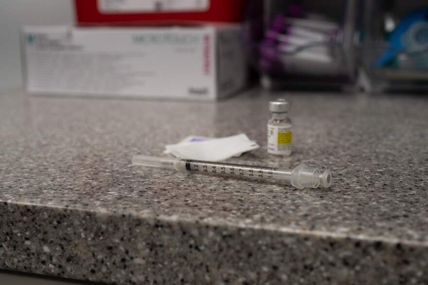 A syringe, bottle of testosterone, and a gauze pad sit on a countertop. 